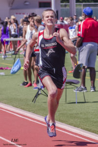 Athlete prepares for pole vault on a track with others watching.