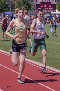 Athlete prepares for pole vault on a track with others watching.