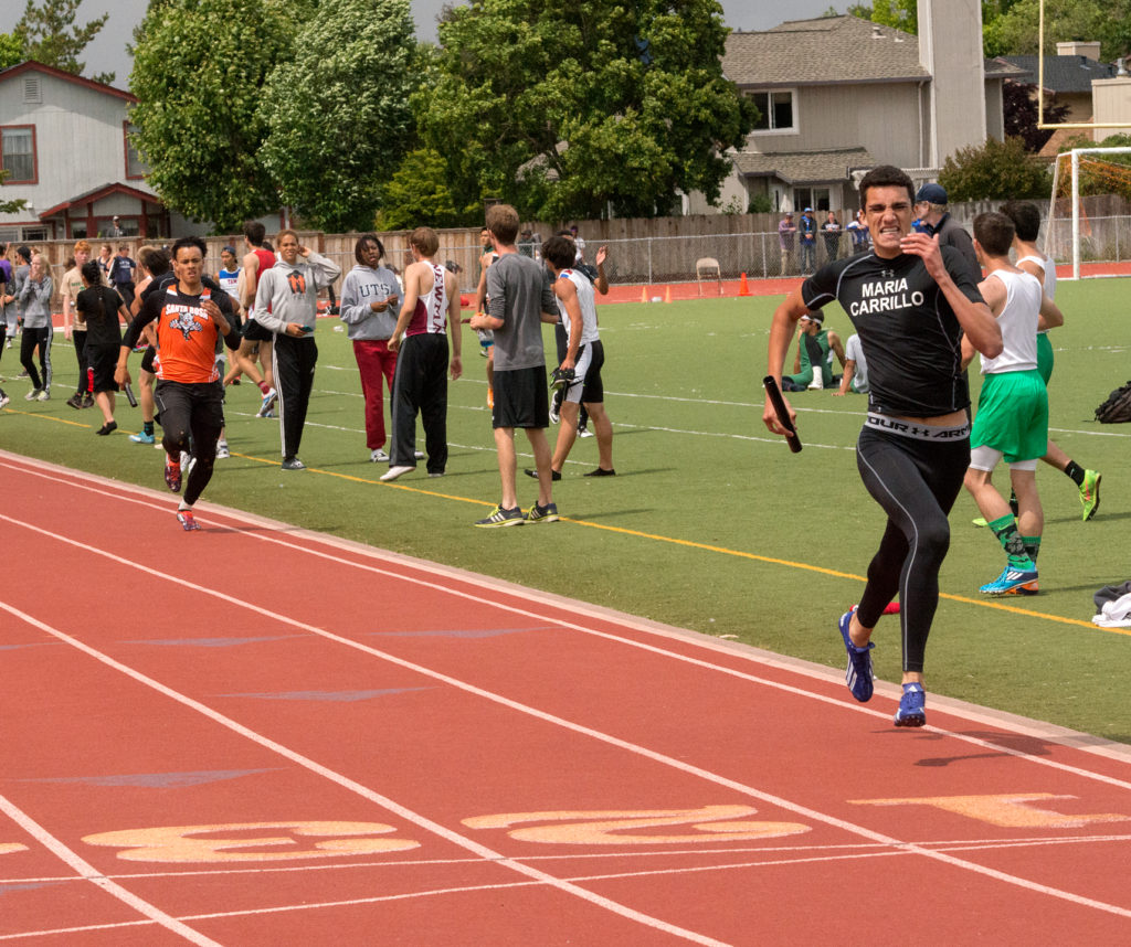 Athlete prepares for pole vault on a track with others watching.