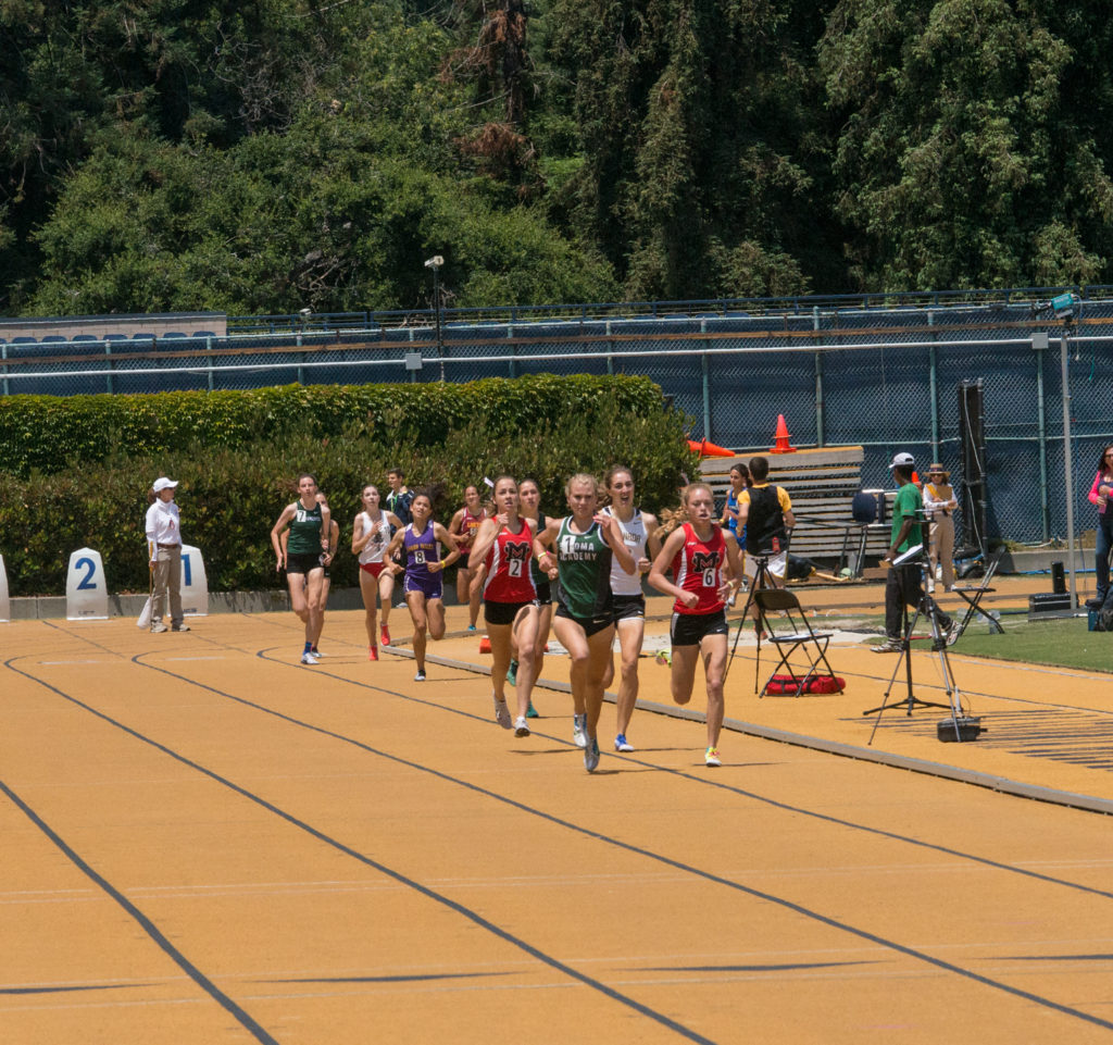 Athlete prepares for pole vault on a track with others watching.