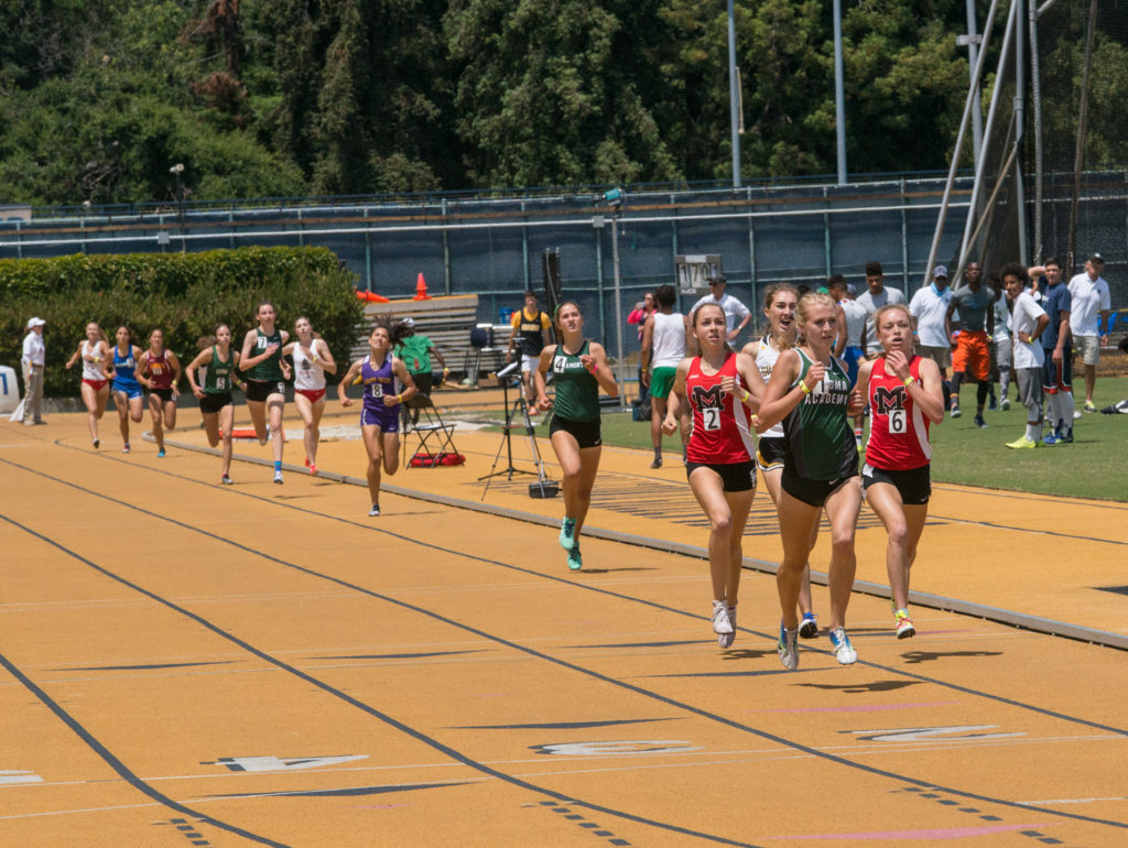 Athlete prepares for pole vault on a track with others watching.