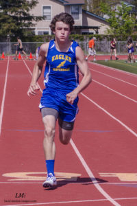 Athlete prepares for pole vault on a track with others watching.