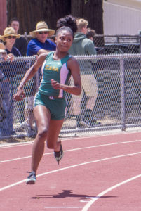 Athlete prepares for pole vault on a track with others watching.