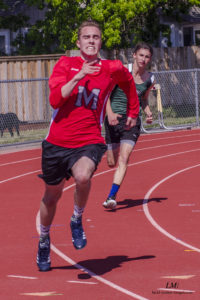 Athlete prepares for pole vault on a track with others watching.