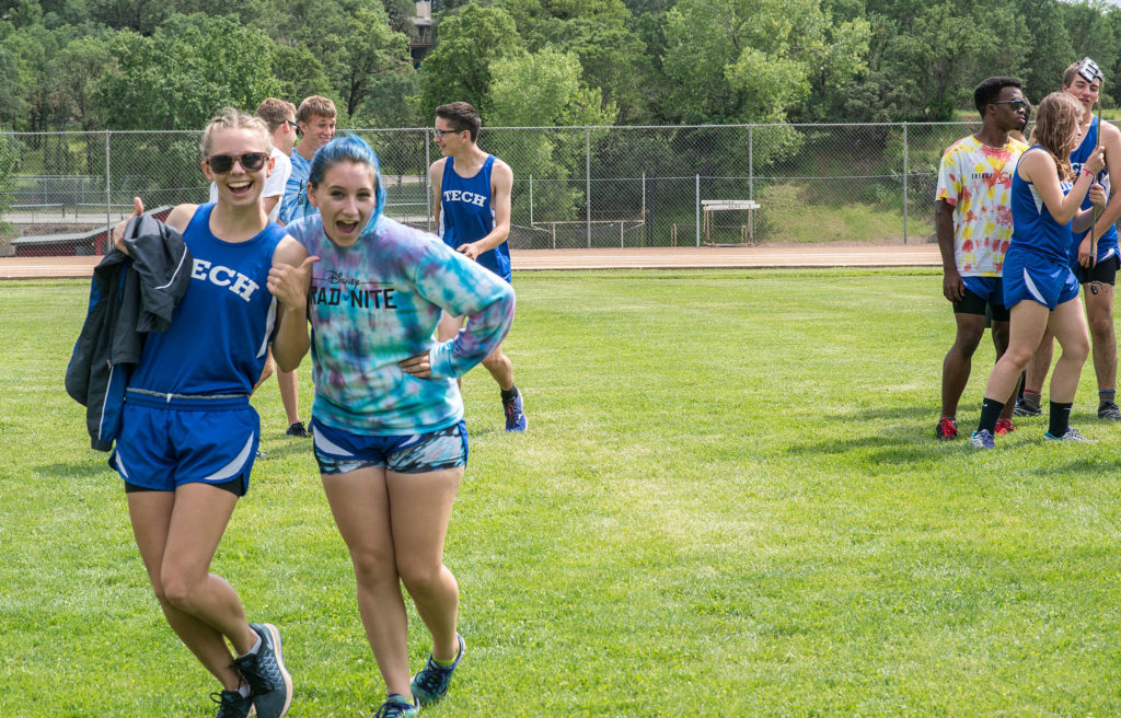 Athlete prepares for pole vault on a track with others watching.