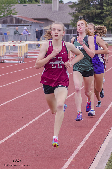 Athlete prepares for pole vault on a track with others watching.