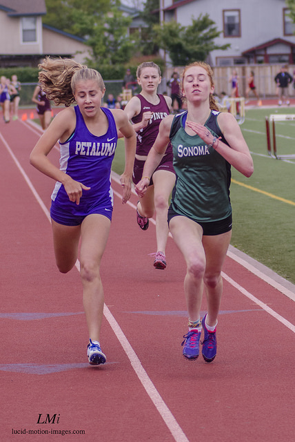 Athlete prepares for pole vault on a track with others watching.