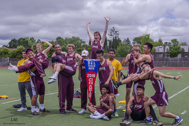 Athlete prepares for pole vault on a track with others watching.