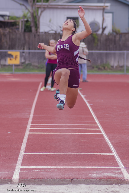 Athlete prepares for pole vault on a track with others watching.