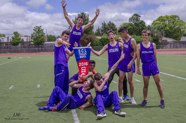 Athlete prepares for pole vault on a track with others watching.