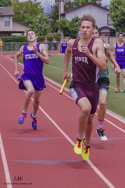Athlete prepares for pole vault on a track with others watching.