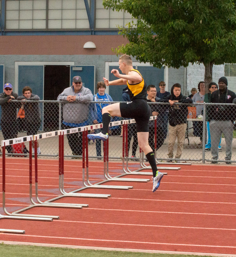 Athlete prepares for pole vault on a track with others watching.
