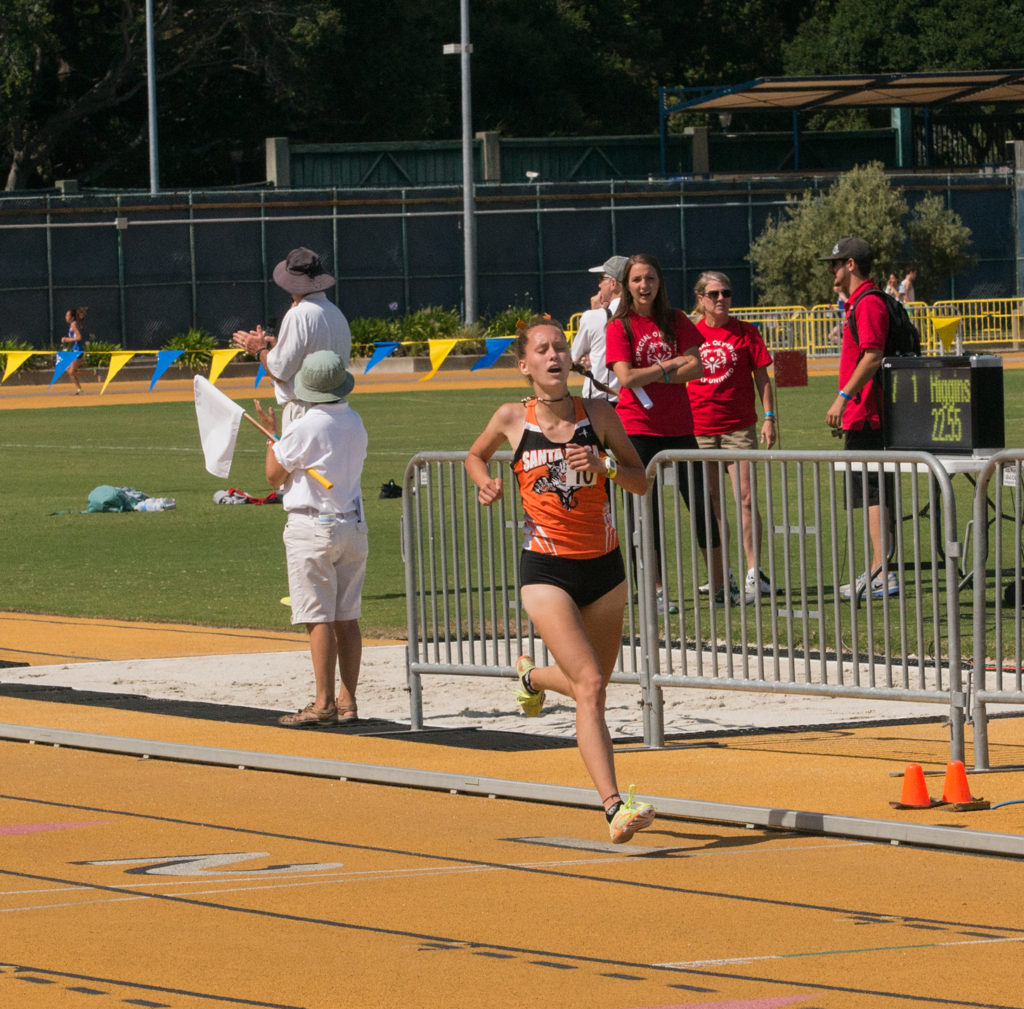 Athlete prepares for pole vault on a track with others watching.