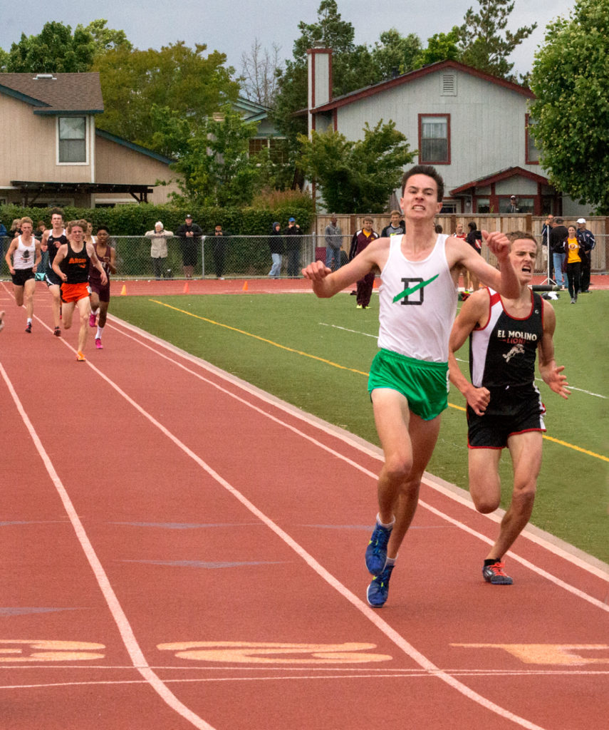Athlete prepares for pole vault on a track with others watching.