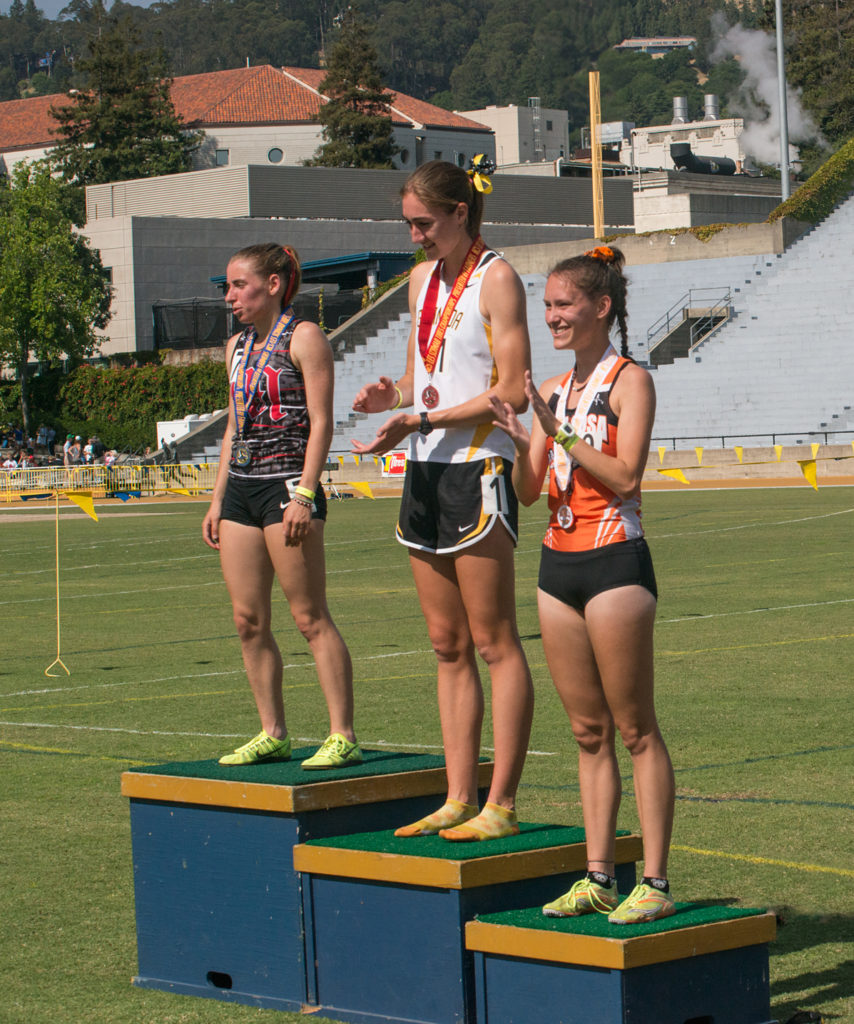 Athlete prepares for pole vault on a track with others watching.