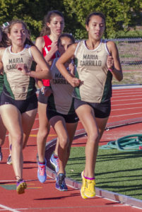 Athlete prepares for pole vault on a track with others watching.