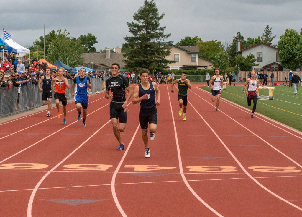 Athlete prepares for pole vault on a track with others watching.
