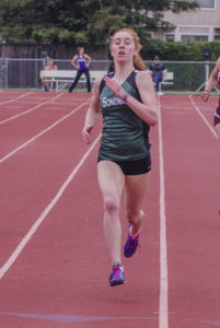 Athlete prepares for pole vault on a track with others watching.
