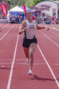 Athlete prepares for pole vault on a track with others watching.