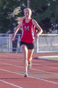 Athlete prepares for pole vault on a track with others watching.
