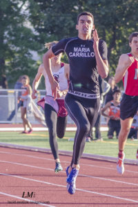 Athlete prepares for pole vault on a track with others watching.
