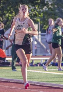 Athlete prepares for pole vault on a track with others watching.