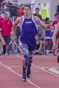 Athlete prepares for pole vault on a track with others watching.