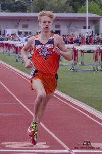 Athlete prepares for pole vault on a track with others watching.