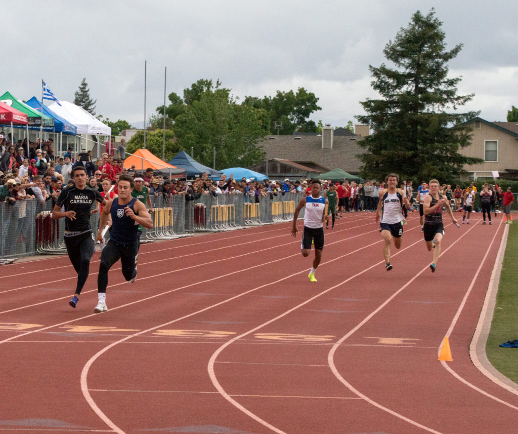Athlete prepares for pole vault on a track with others watching.