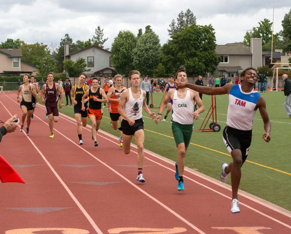 Athlete prepares for pole vault on a track with others watching.