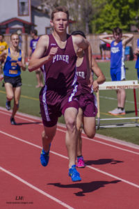 Athlete prepares for pole vault on a track with others watching.