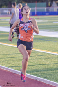 Athlete prepares for pole vault on a track with others watching.