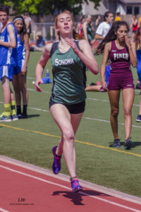 Athlete prepares for pole vault on a track with others watching.