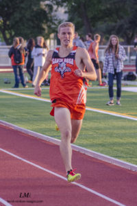 Athlete prepares for pole vault on a track with others watching.