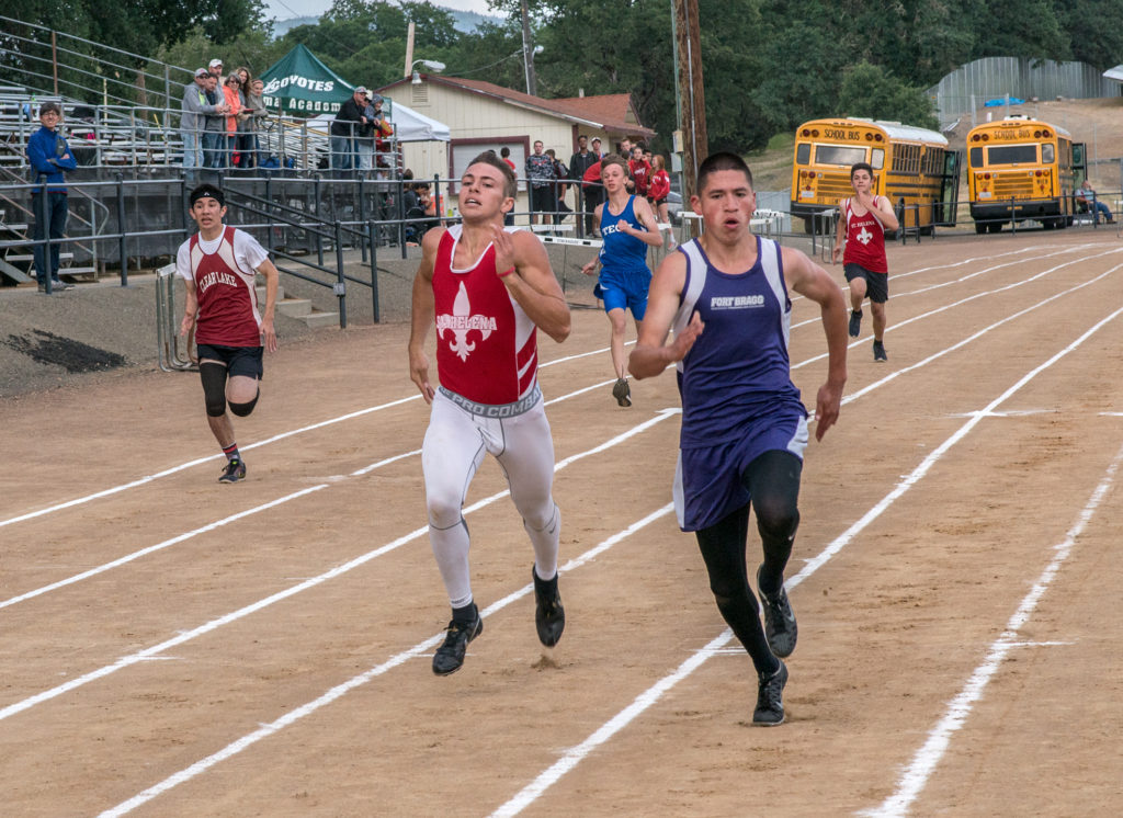 Athlete prepares for pole vault on a track with others watching.