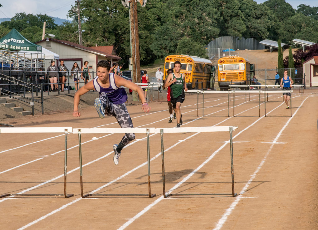 Athlete prepares for pole vault on a track with others watching.