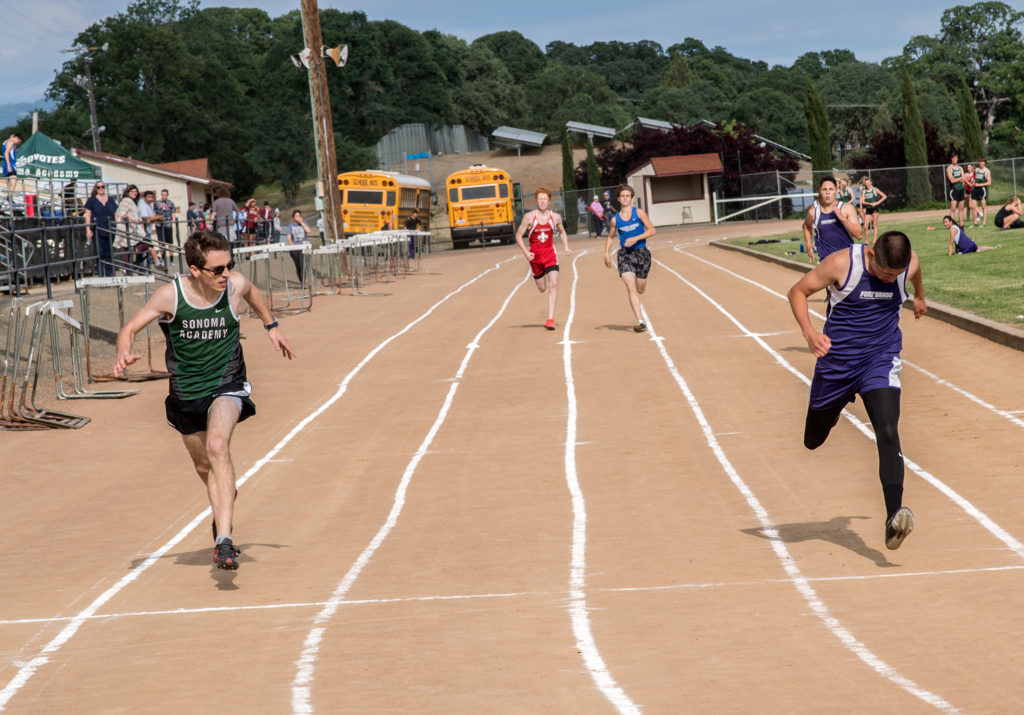 Athlete prepares for pole vault on a track with others watching.