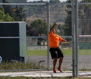 Athlete prepares for pole vault on a track with others watching.