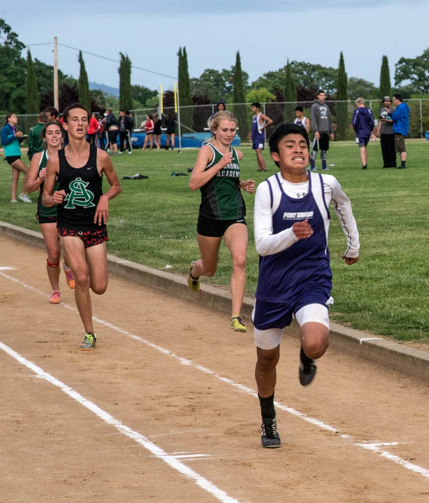 Athlete prepares for pole vault on a track with others watching.