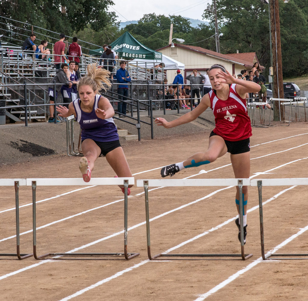 Athlete prepares for pole vault on a track with others watching.