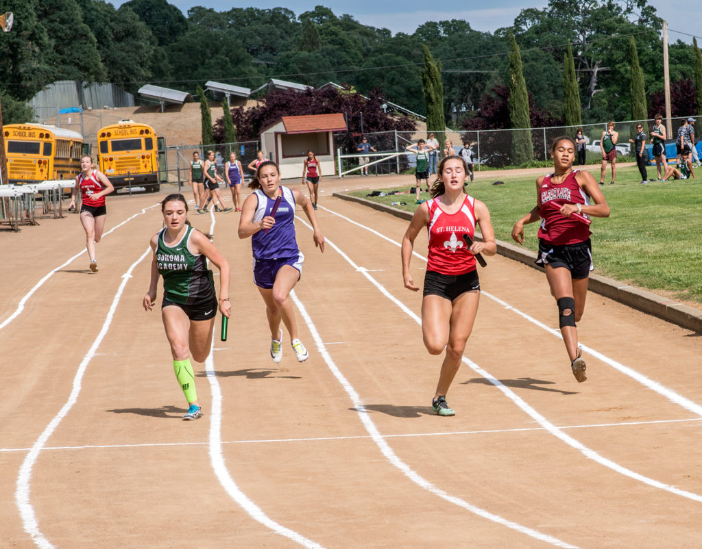 Athlete prepares for pole vault on a track with others watching.