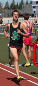 Athlete prepares for pole vault on a track with others watching.