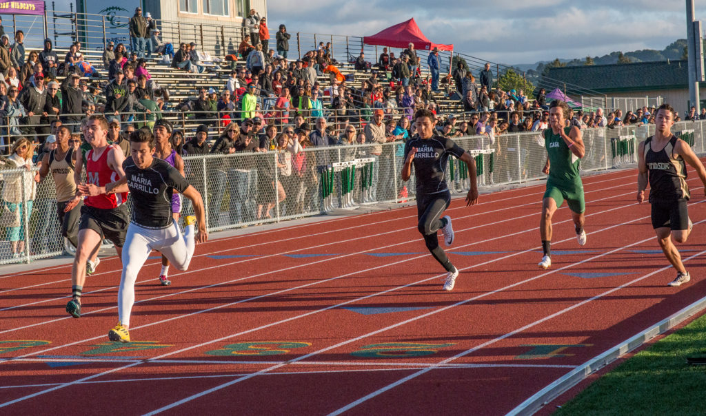 Athlete prepares for pole vault on a track with others watching.