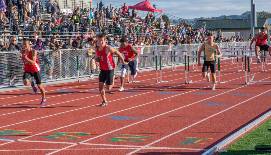 Athlete prepares for pole vault on a track with others watching.
