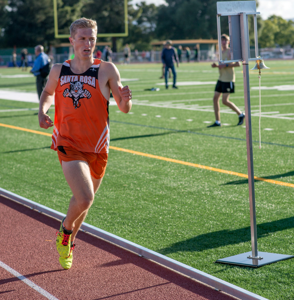 Athlete prepares for pole vault on a track with others watching.