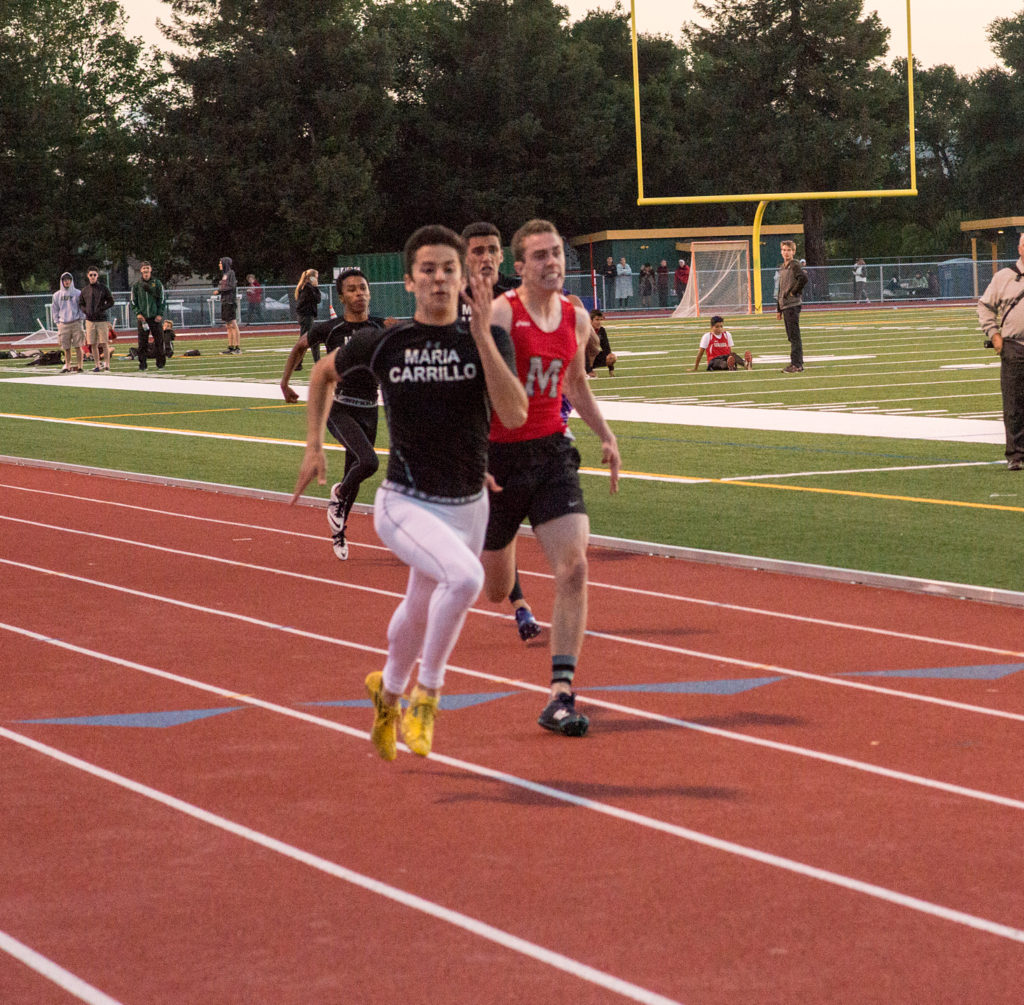 Athlete prepares for pole vault on a track with others watching.