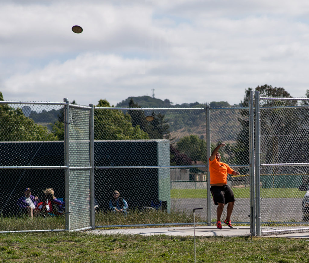 Athlete prepares for pole vault on a track with others watching.