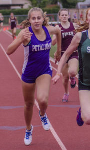 Athlete prepares for pole vault on a track with others watching.