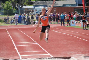 Athlete prepares for pole vault on a track with others watching.