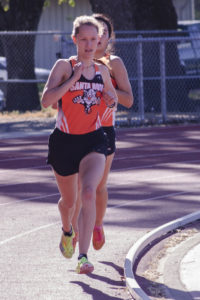 Athlete prepares for pole vault on a track with others watching.